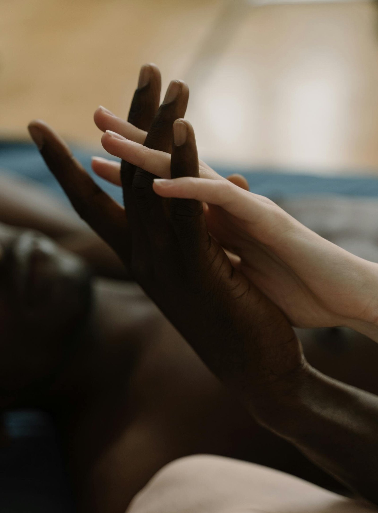 Close-up of an interracial couple's hands intertwined, symbolizing love and unity.