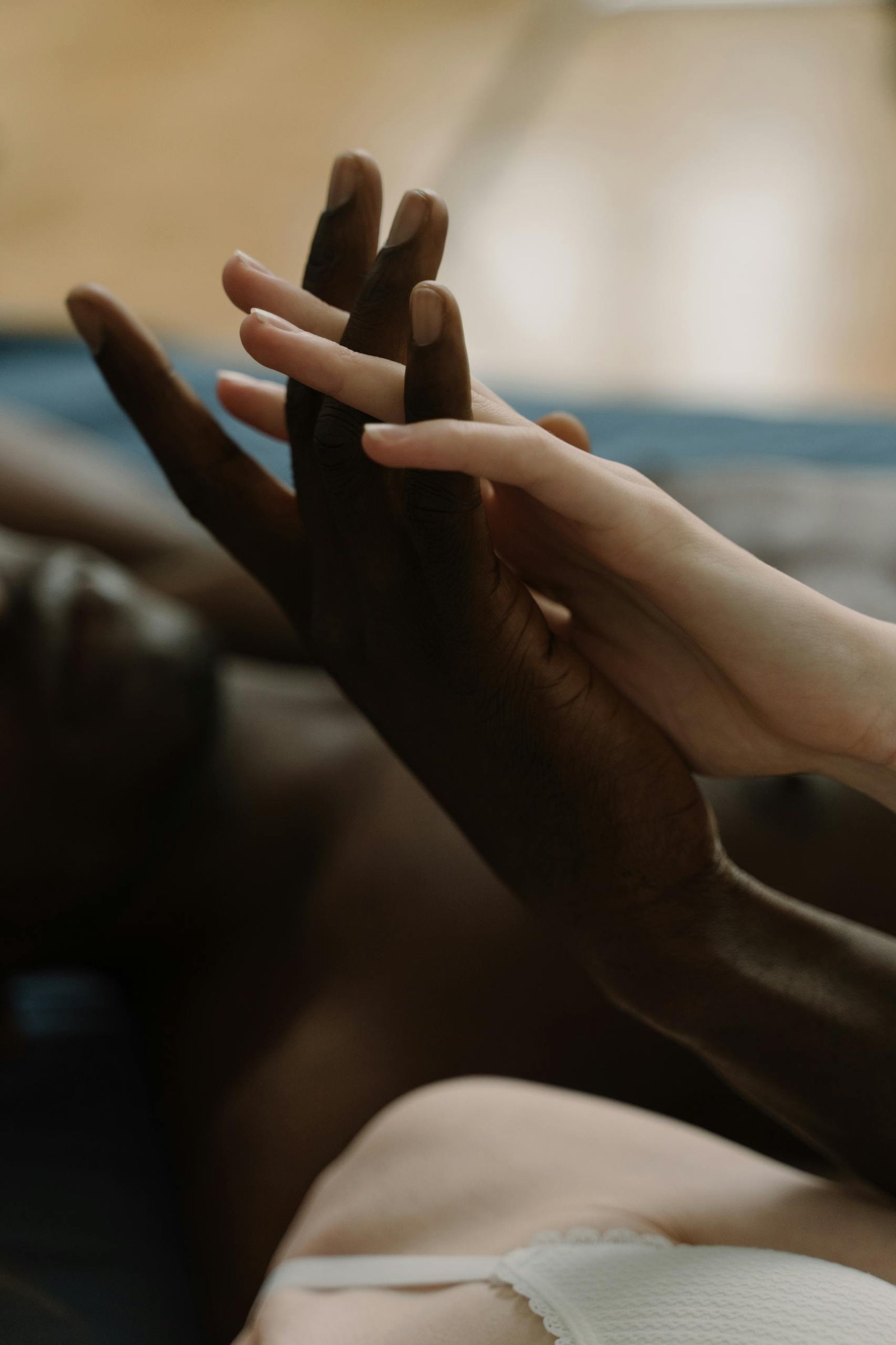 Close-up of an interracial couple's hands intertwined, symbolizing love and unity.